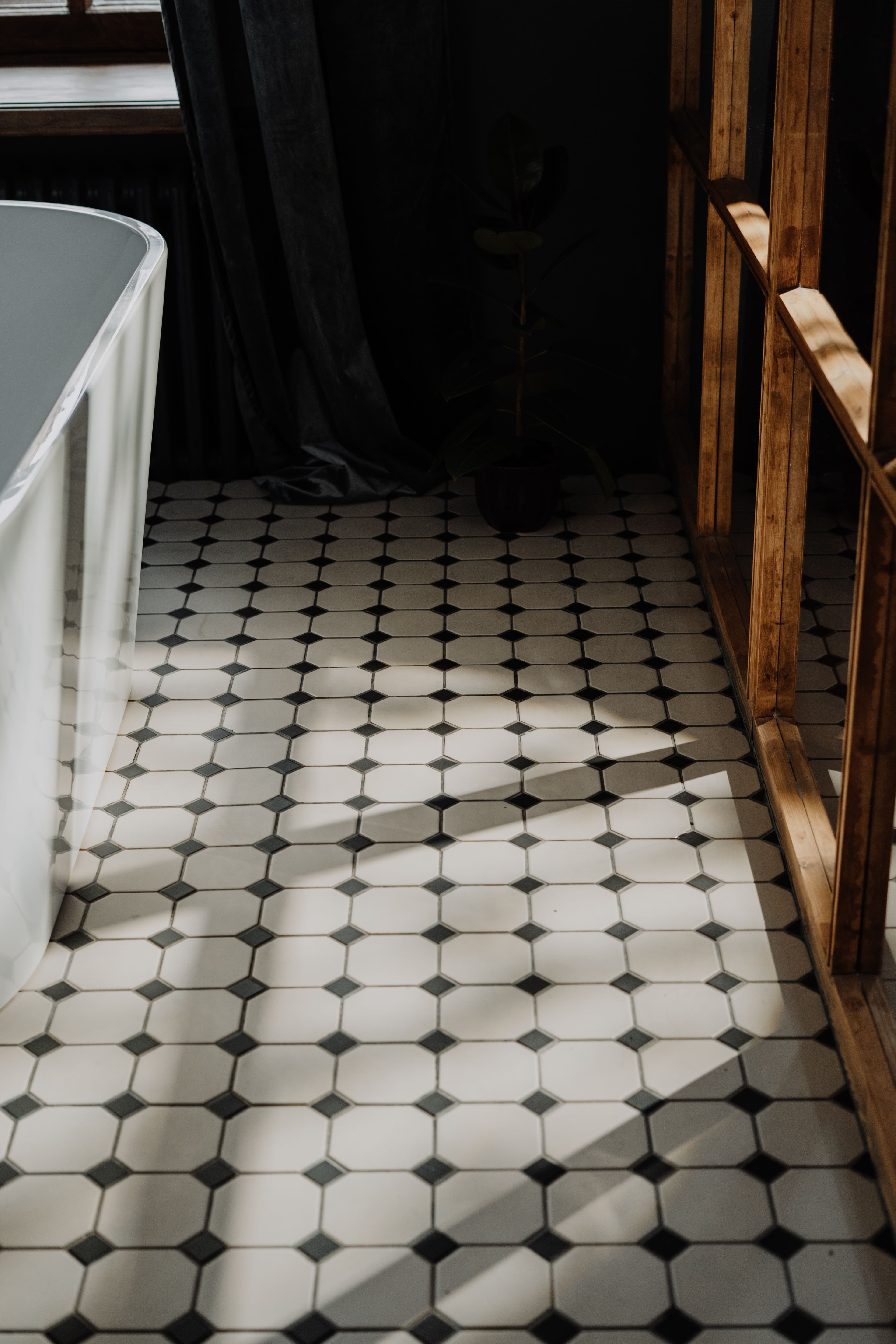 Patterned tile-effect vinyl floor in a bathroom with a freestanding bath