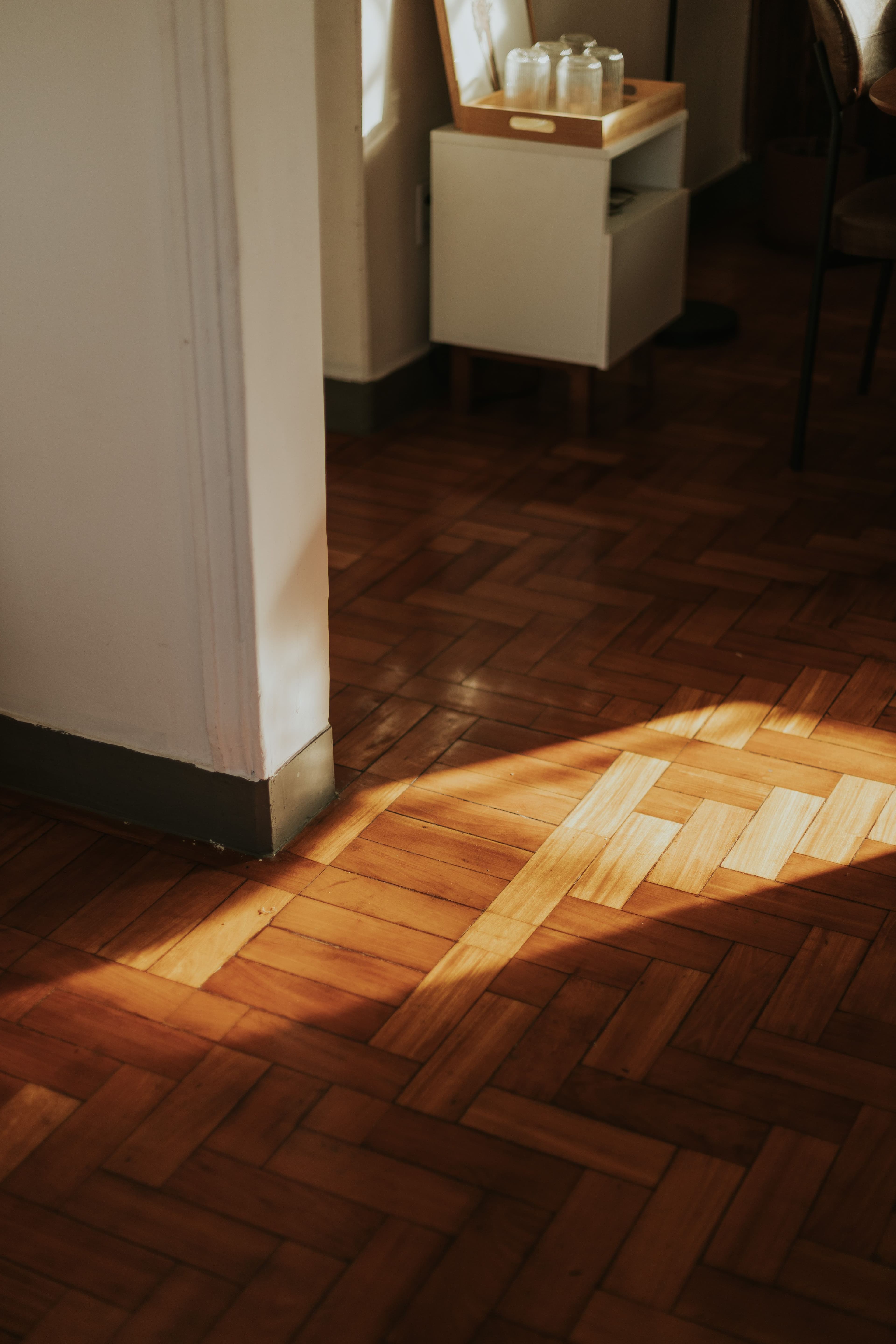 Sunlit herringbone parquet floor beside a doorway
