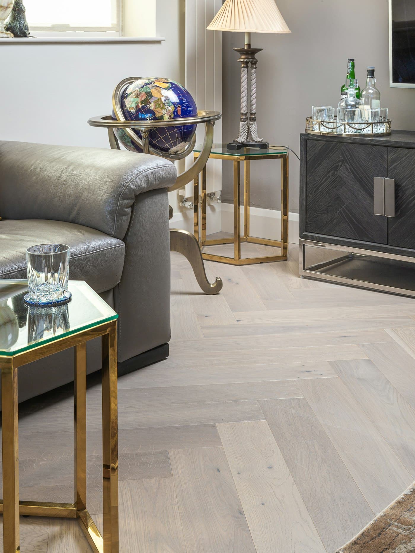 Open-plan living room with herringbone timber flooring, a sofa and a sideboard