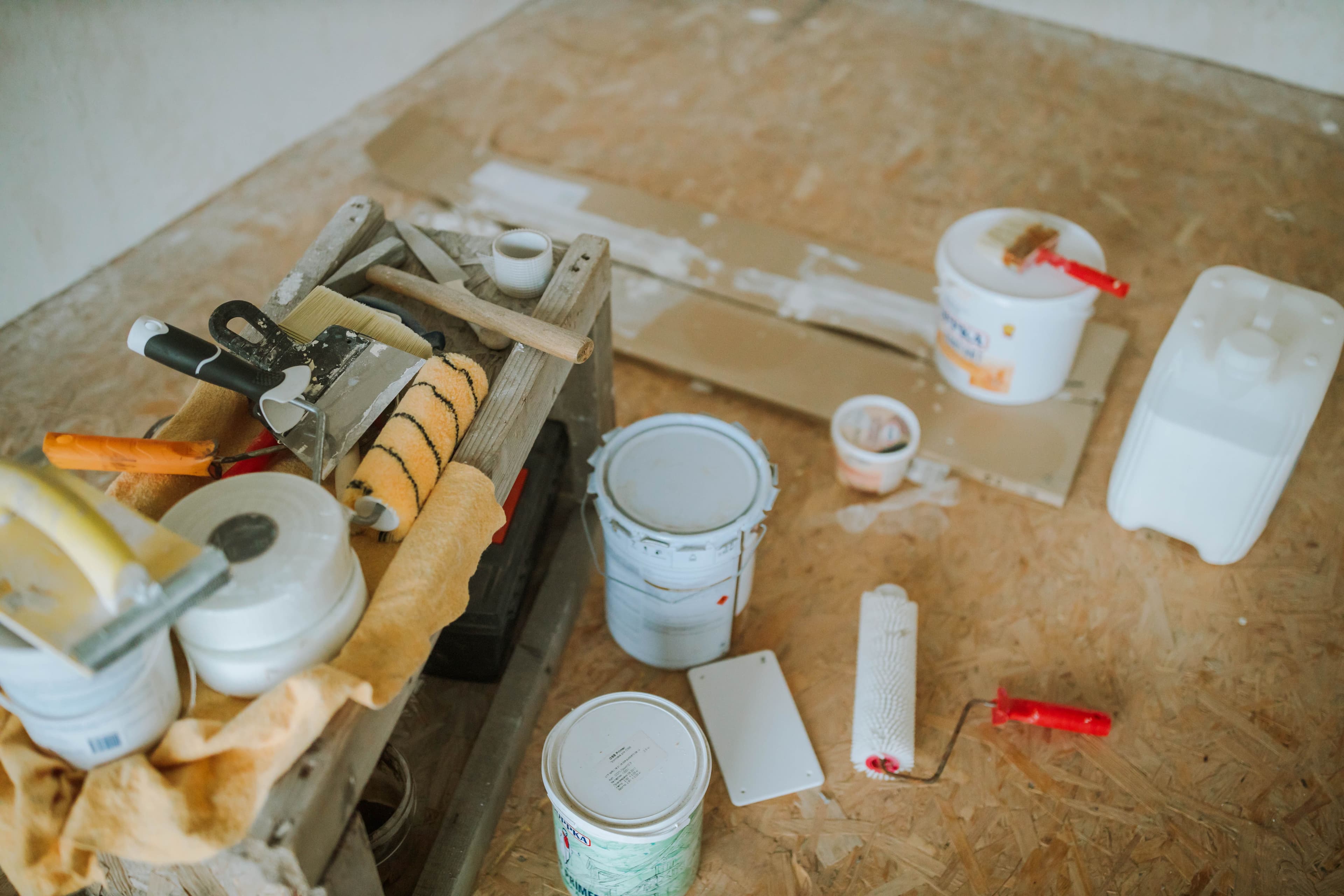 Paint tins, rollers and a tray laid out on a workbench